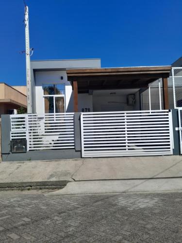a house with a white fence in front of it at Morada do Sol in Passo De Torres