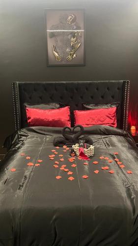 a bed with a black comforter and red pillows at Romantic apartment near Paris in Maintenon