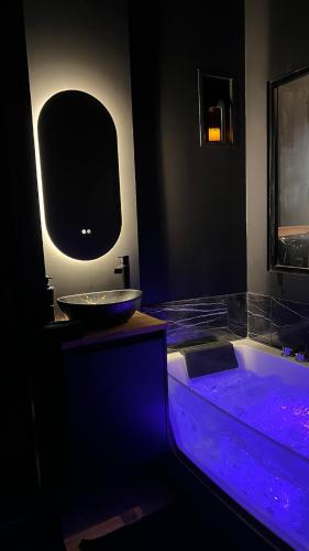 a bathroom with a tub and a sink with purple lights at Romantic apartment near Paris in Maintenon