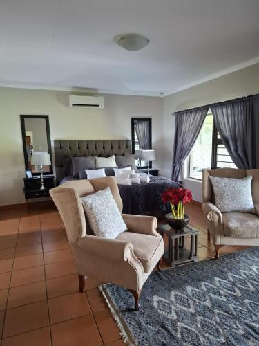 a bedroom with a bed and a couch and chairs at Zacks Country Stay Self-catering in Krugersdorp