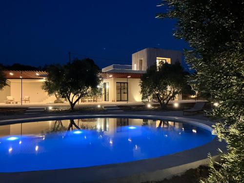 a large blue pool in front of a building at night at Villa Fengari in Evangelismós