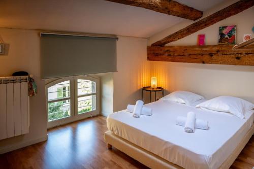 une chambre avec un grand lit blanc et une fenêtre dans l'établissement Appartement de charme au coeur d'Avignon, à Avignon
