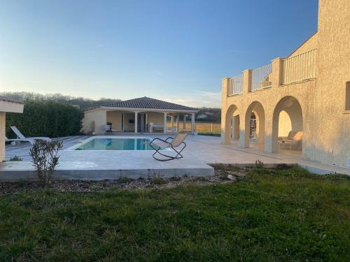 une chaise assise devant une maison avec piscine dans l'établissement L Ecrin de Lidia close to MEETT Air conditioning Parking, à Aussonne