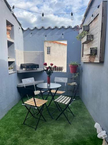 un patio avec une table et des chaises sur l'herbe dans l'établissement Charmante Maison de Village avec Terrasse, à Olonzac
