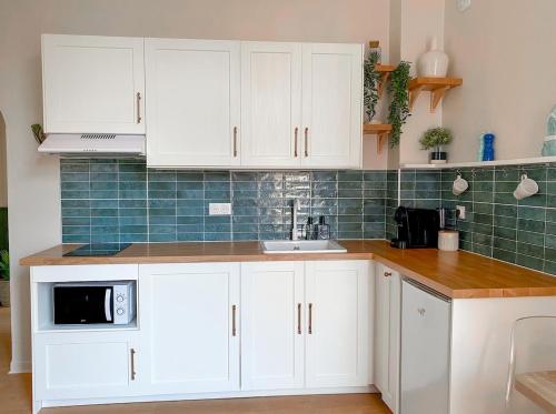 une cuisine avec des armoires blanches et un micro-ondes dans l'établissement Charmant 2P avec Balcon, Proche Centre, à Cannes