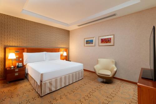 a hotel room with a bed and a chair at Holiday Inn Kuwait by IHG in Kuwait