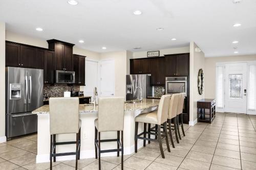 a kitchen with a bar with chairs and appliances at Extravagant Home With Movie Theater, Private Pool And Waterpark & Resort Access At Encore Resort - 241Fl in Kissimmee