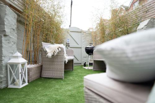a small backyard with green grass and wicker chairs at Driftwood House in Bournemouth