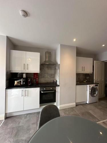 a kitchen with white cabinets and a table with chairs at Abbey Apartments in Dublin