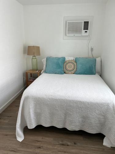 a bedroom with a bed with blue pillows and a fan at Cozy Cabin in Brazoria