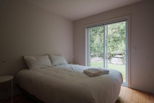 Un dormitorio con una cama y una ventana grande. en Chalets OST Shefford FORFAIT GROUPE, en Shefford