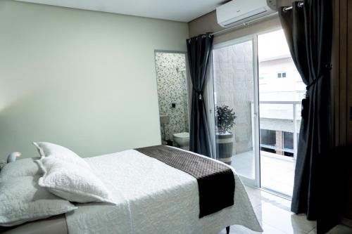 a bedroom with a bed and a sliding glass door at MD Recanto Iguaçu in Foz do Iguaçu