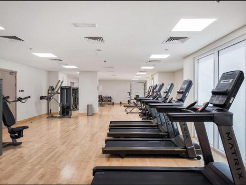 a gym with a row of treadmills and machines at Noor Homes - Luxury Approved by the Department of Culture and Tourism, Abu Dhabi in Yas Island in Abu Dhabi