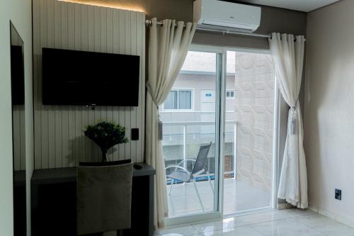 a living room with a television and a sliding glass door at MD Recanto Iguaçu in Foz do Iguaçu