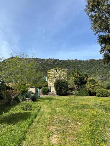 a stone house with a hill in the background at L'Aghjalle in Santa-Reparata-di-Balagna