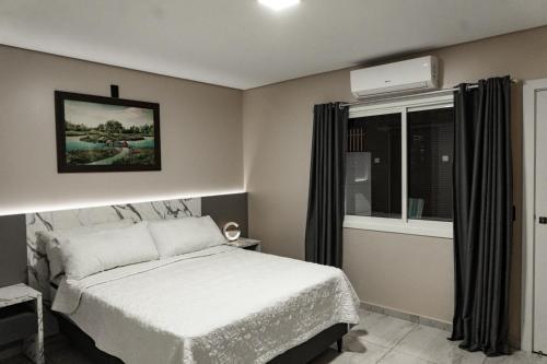 a bedroom with a white bed and a window at MD Recanto Iguaçu in Foz do Iguaçu