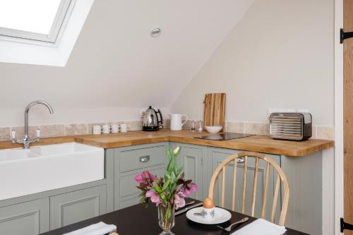 a kitchen with a table with a vase of flowers at The Roost in Biddlestone