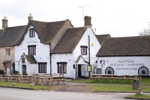 a white building with wooden benches in front of it at The Roost in Biddlestone