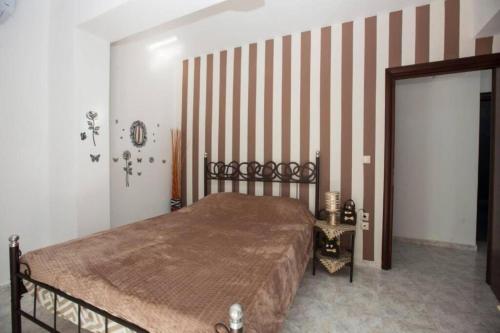 a bedroom with a bed and a striped wall at Natural Quiet Accommodation 2 - Faliraki in Kalithies