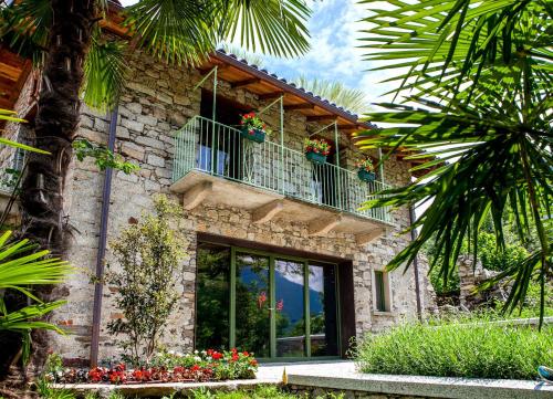 a stone building with two balconies with flowers on it at Ca da la Butina in Mergozzo