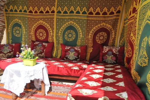 a room with red beds and a table with flowers at Dar Fatimazahra in Fès
