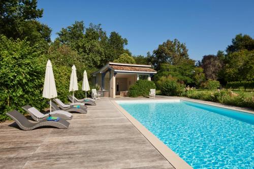 - une rangée de chaises et de parasols à côté de la piscine dans l'établissement Gites La Sauvageonne, à Saint-Palais