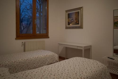 a room with two beds and a table and a window at Casa Jack in San Giorgio di Piano