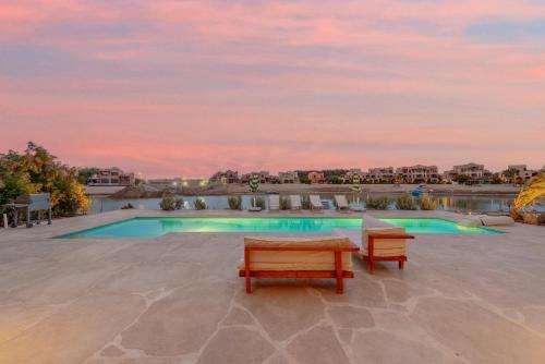 a patio with two benches and a swimming pool at Dream Beach House on Island 3BR Priv Pool Sabina El Gouna in Hurghada
