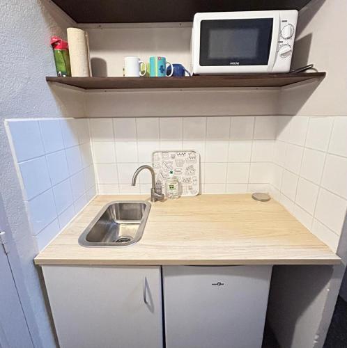 une petite cuisine avec un évier et un micro-ondes dans l'établissement Elégant studio Avignon centre, à Avignon