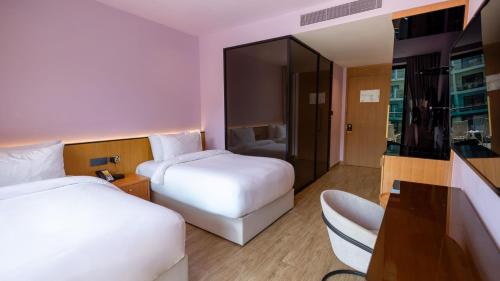 a hotel room with two beds and a desk at voco Dubai Monaco, the Heart of Europe by IHG in Dubai