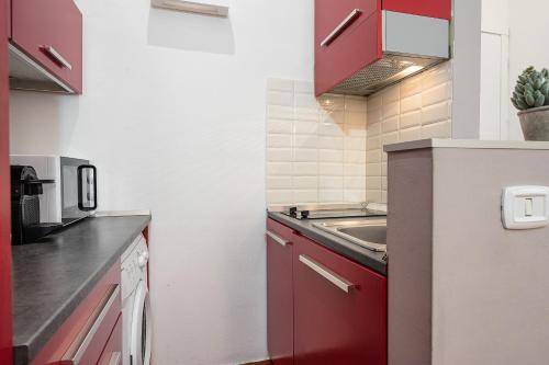 a kitchen with red cabinets and a sink at Classbnb - Two apartments 400 meters from the Duomo in Milan