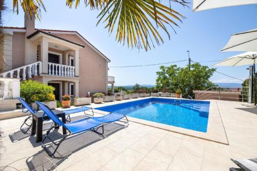 una piscina di fronte a una casa con sedie blu e una casa di Ferienwohnung für 6 Personen ca 74 qm in Sveti Vid-Miholjice, Kvarner Bucht Krk a Sveti Vid-Miholjice