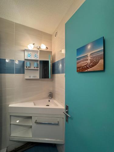 La salle de bains est pourvue d'un lavabo blanc et d'une porte bleue. dans l'établissement Le Petit Bora-Marseillan Plage -Residence Bora Bora-400m plage d'honneur, à Marseillan