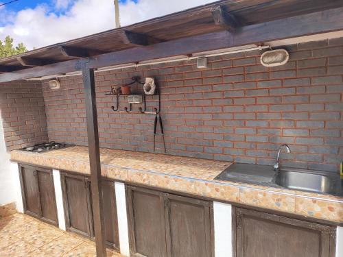 une cuisine extérieure avec un évier et un mur en briques dans l'établissement Casa de Campo Hiurma, à Triquivijate