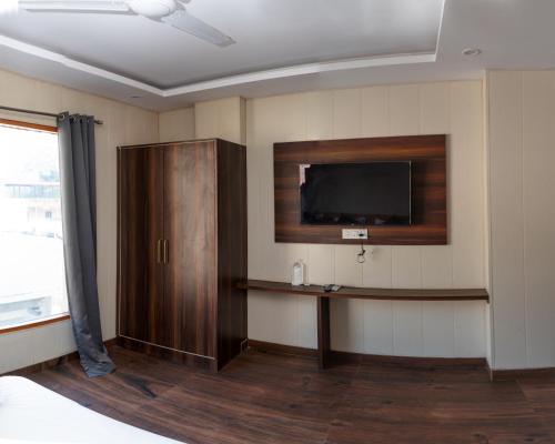 a room with a tv on the wall and a table at Hotel Aghore Shaktipeeth in Narendranagar
