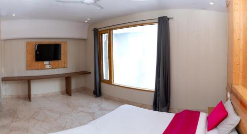 a bedroom with a bed and a window and a tv at Hotel Aghore Shaktipeeth in Narendranagar