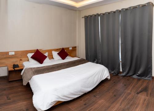 a bedroom with a large white bed with red pillows at Hotel Aghore Shaktipeeth in Narendranagar
