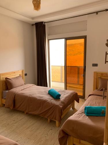 a bedroom with two beds and a large window at Nomad Surf Lodge in Imsouane