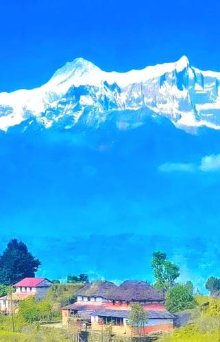 a snow covered mountain with a house in front of it at Aditya Homestay Dalhousie in Dalhousie