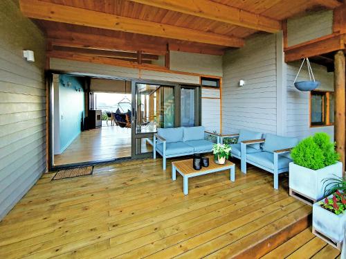 a porch with blue chairs and a wooden floor at Main House - Maison Mahogany - 100sqm design with lagoon view and jacuzzi in Knysna