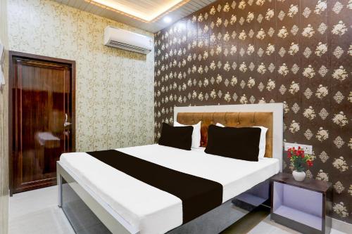 a bedroom with a bed and a wall with flowers at Super Hotel O Radha kunj By Namasya Retreat International in Prayagraj