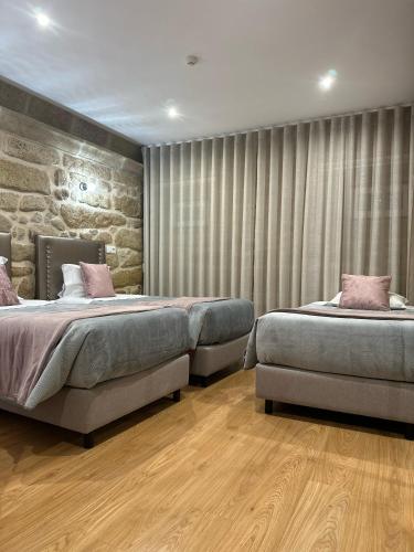 a bedroom with two beds and a stone wall at Alojamento Central in Chaves