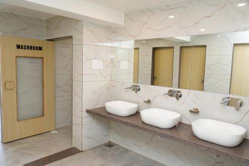 a bathroom with two sinks and two mirrors at City Dormitory in Ahmedabad