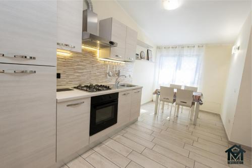 a kitchen with white cabinets and a table and chairs at Le Ghiande Appartamento Roma in Infernetto