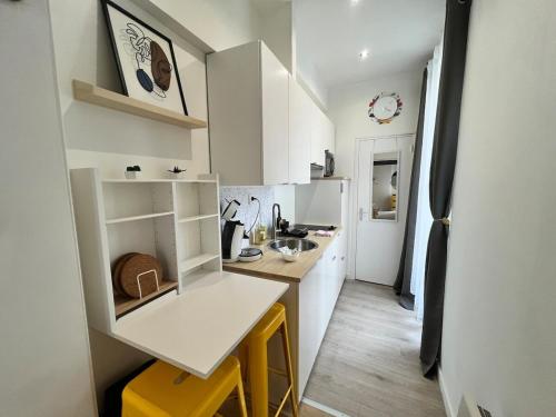 une petite cuisine blanche avec un comptoir et des tabourets jaunes dans l'établissement Le CoCon Nantais 2pers Wi-Fi TV, à Nantes