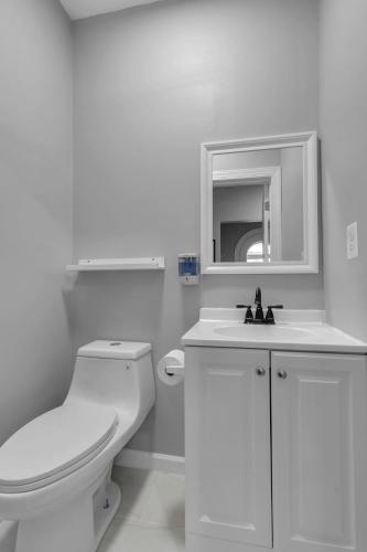 a white bathroom with a toilet and a sink at Close to Niagara Fall Dream Home in Niagara Falls