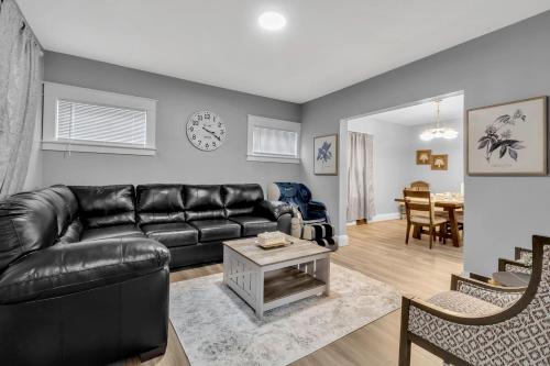 a living room with a black leather couch and a table at Close to Niagara Fall Dream Home in Niagara Falls