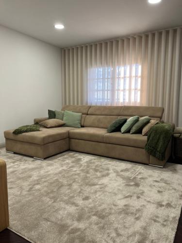a living room with a large couch in front of a window at Casa São Domingos in Lousada