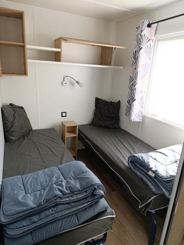 une petite chambre avec deux lits et une fenêtre dans l'établissement Camping Siblu Le Montourey, à Fréjus