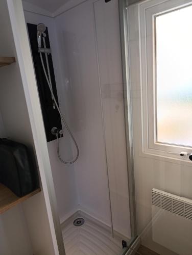 une douche avec une porte en verre à côté d'une fenêtre dans l'établissement Camping Siblu Le Montourey, à Fréjus